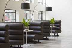 green plants in silver plant pots in black booth seating