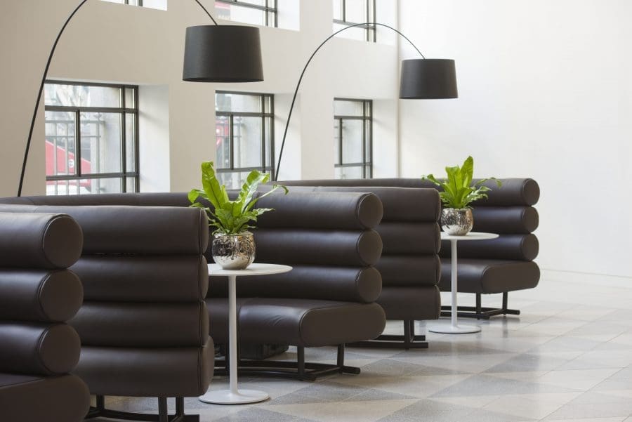 green plants in silver plant pots in black booth seating